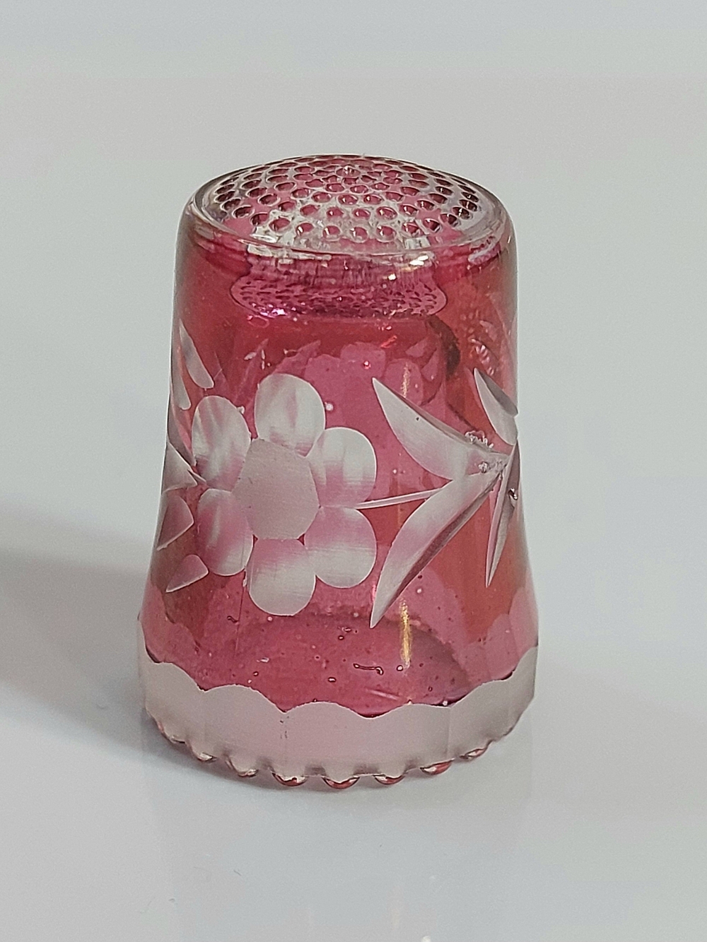 Vintage etched cranberry glass thimble featuring a delicate floral motif.